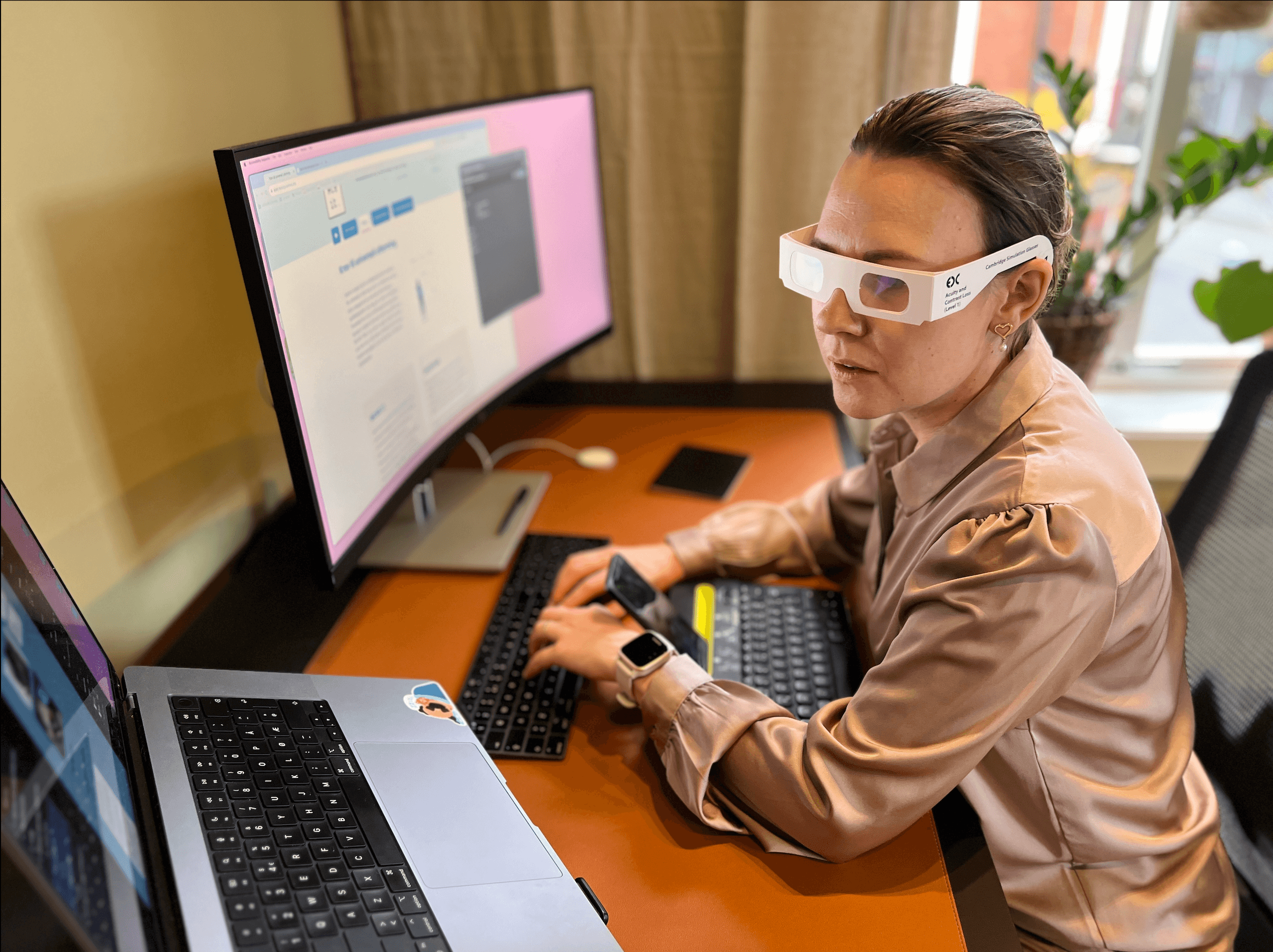 Saja is testing a website with magnification, an external keyboard, and glasses that simulate vision impairment.